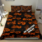 A made bed in a bedroom setting featuring a black bedding set with an orange graffiti-style pattern of demolished cars and the words 'DEMOLITION DERBY' in white. The room includes a white chair, side table, and shelving.