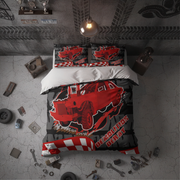 A racing-themed bedding set featuring a red race car and checkered patterns, styled in a dark, industrial-themed bedroom with concrete floors and car parts scattered around.