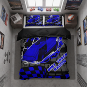 A top-down view of a bed dressed in a racing-themed bedding set, placed in a styled bedroom. The bedding features a blue and black dirt track racing car design with 'DIRT TRACK RACING' text and a checkered pattern.