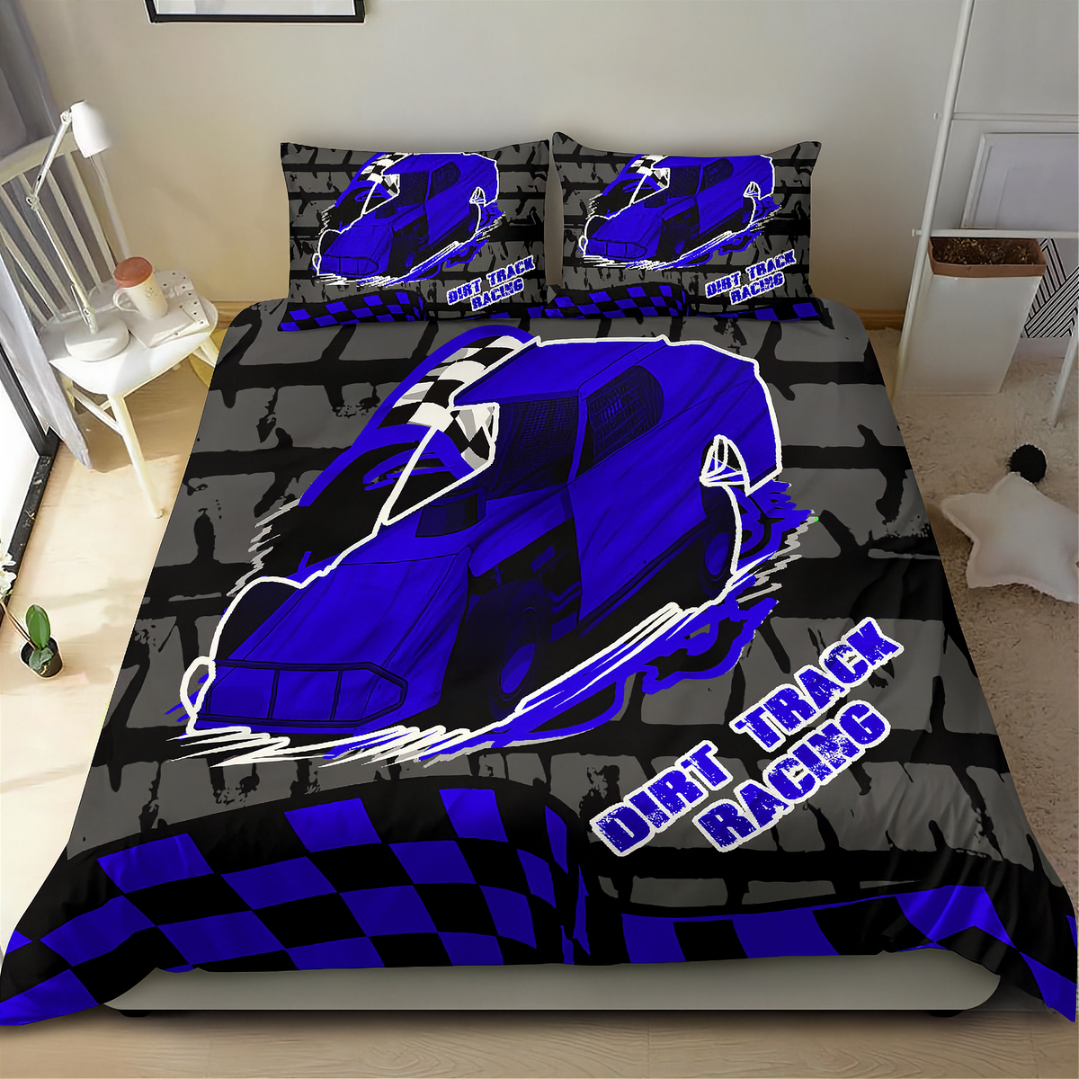 A bedding set featuring a duvet cover and two pillowcases with a blue dirt track racing car design on a black and gray background, displayed on a bed in a bedroom setting.