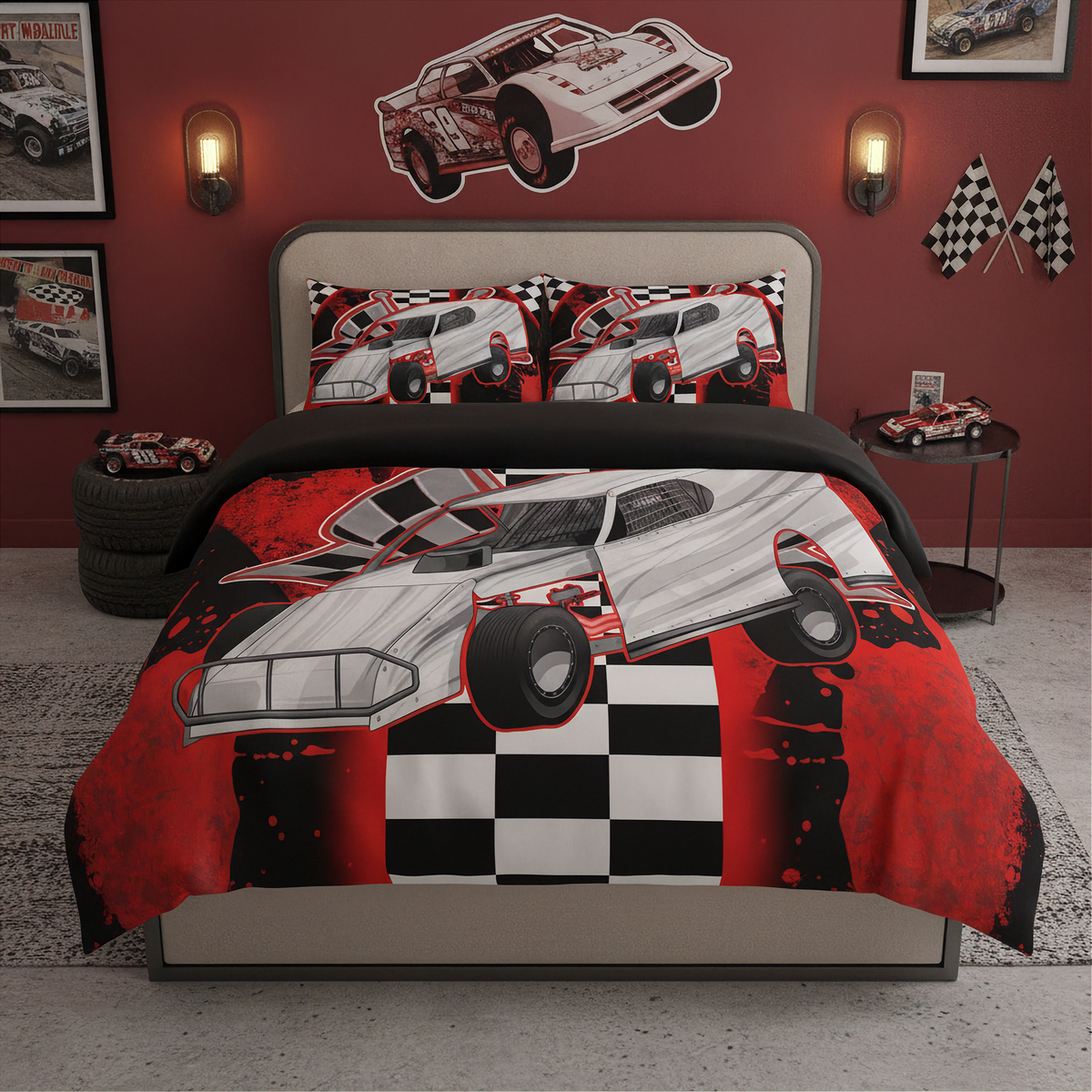 A children's bedroom set featuring a bed dressed in a red, black, and white race car print comforter and matching pillow shams, set against a red wall decorated with race car wall decals, framed pictures, and toy cars.
