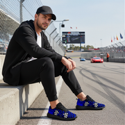 Man sitting on a race track wearing black and blue sneakers.