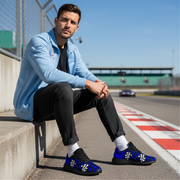 Man sitting on a race track wearing blue sneakers with a checkered pattern.