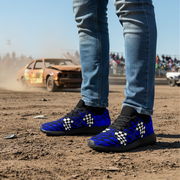 Person wearing blue checkered shoes on a dirt track with a car in the background