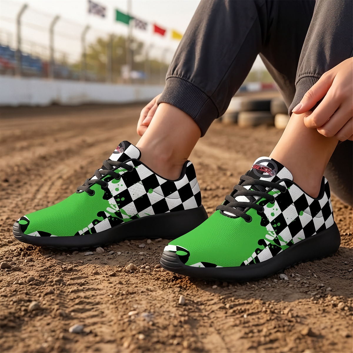 A person sitting outdoors on dirt wearing low-top sneakers with a bright green and black-and-white checkered design, black laces, and black soles.