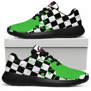 A pair of low-top sneakers shown on a white background, with one shoe resting on top of a white box and the other below. The shoes have a black and white checkerboard pattern on the sides and tongue, bright green paint-splatter overlays, and black soles and laces.