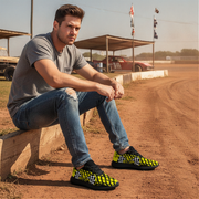 Man sitting on a concrete block at a race track wearing checkered shoes.