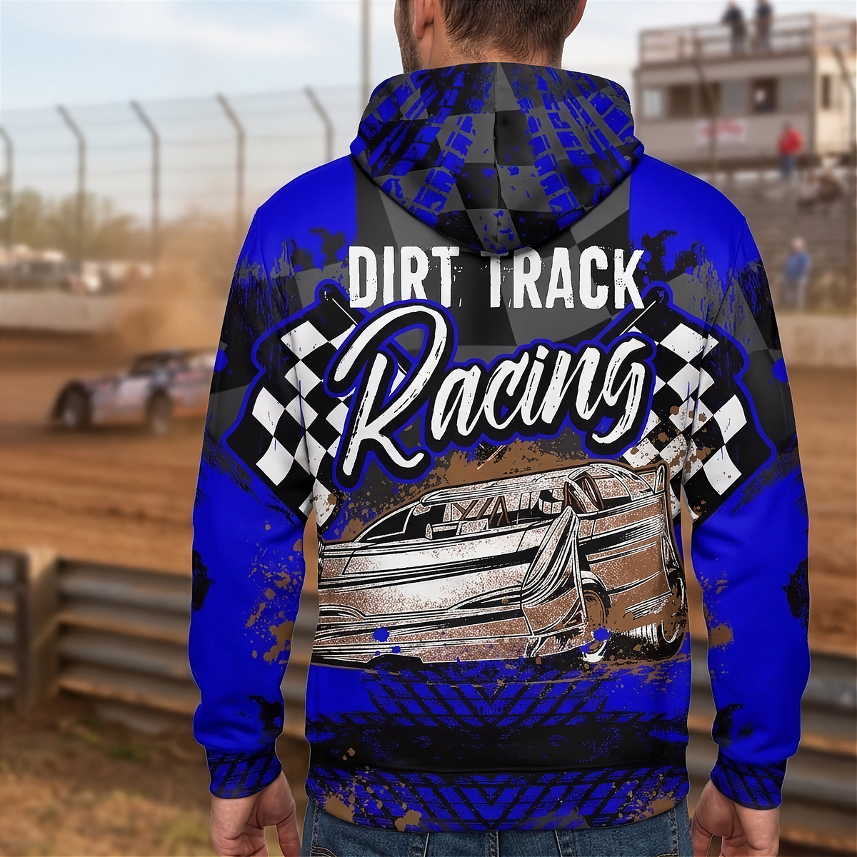 A man viewed from behind wearing a blue and black hooded sweatshirt with a 'Dirt Track Racing' graphic featuring a race car and checkered flags, set against a blurred dirt track background.