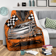Decorative blanket with a car and racing flags design on a couch in a living room.