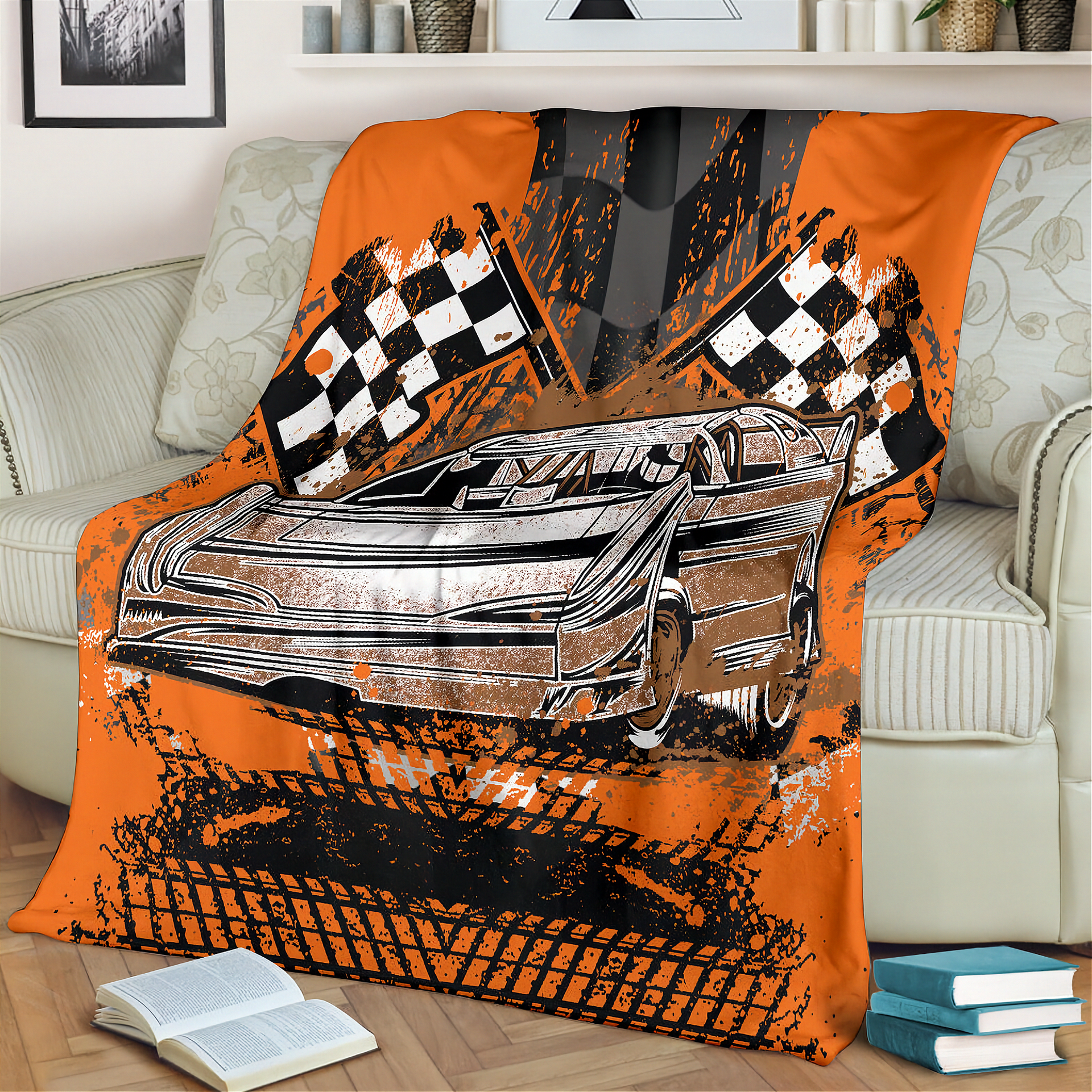 Orange blanket with car and checkered flag design draped over a couch in a living room.