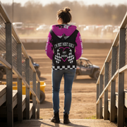 Woman wearing a pink sherpa hoodie with text and graphics, standing on a track.