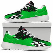 A pair of low-top athletic sneakers with a vibrant green and black paint-splatter design, white laces, and a black-and-white checkered pattern near the toe. One shoe is displayed on top of a white shoebox, and the other is shown from the side profile below, set against a clean white background.