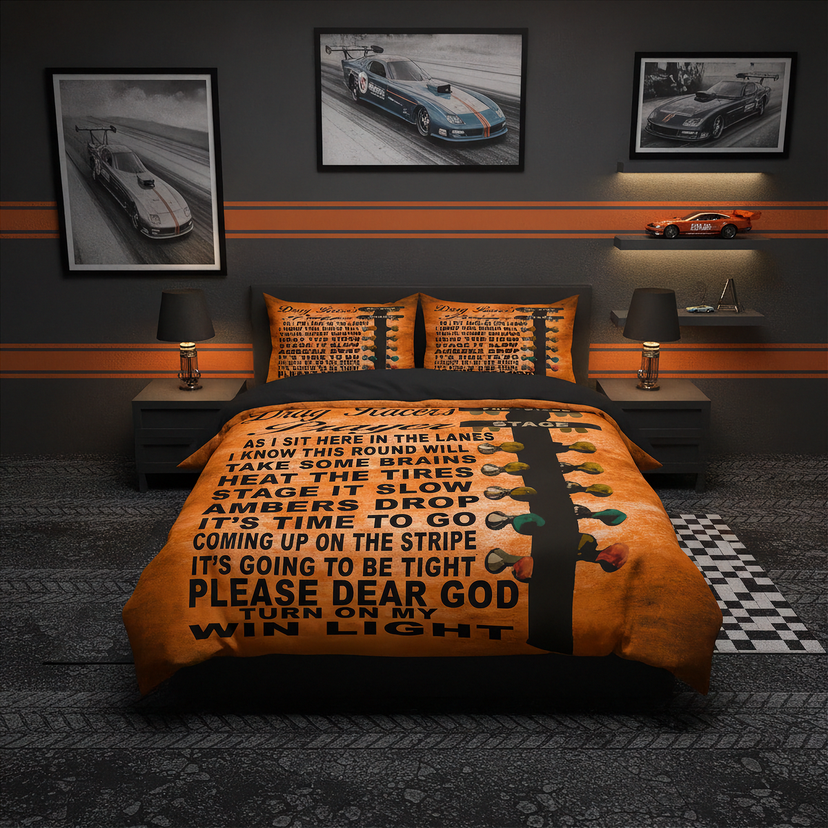 A bed dressed in an orange and black racing-themed bedding set with a large printed motivational quote and a striped light bulb graphic, shown in a styled bedroom with racing wall art, bedside lamps, and a small car model.