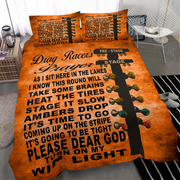 A bed dressed in an orange and black drag racer themed bedding set, featuring a large drag racer prayer text design and a guitar headstock graphic with colorful taillights. The set includes a duvet cover and two matching pillowcases, shown in a modern bedroom setting.