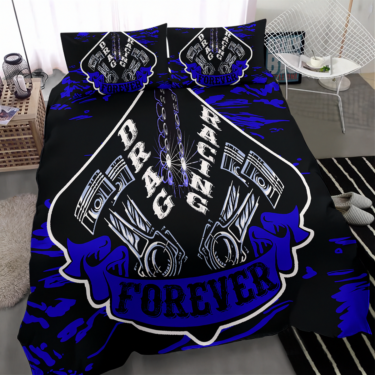 A black bedding set with a bold blue and white drag racing graphic, shown on a bed in a modern bedroom setting. The set includes a duvet cover and two matching pillowcases featuring a large shield design with pistons, chains, and the words 'DRAG RACING FOREVER'.