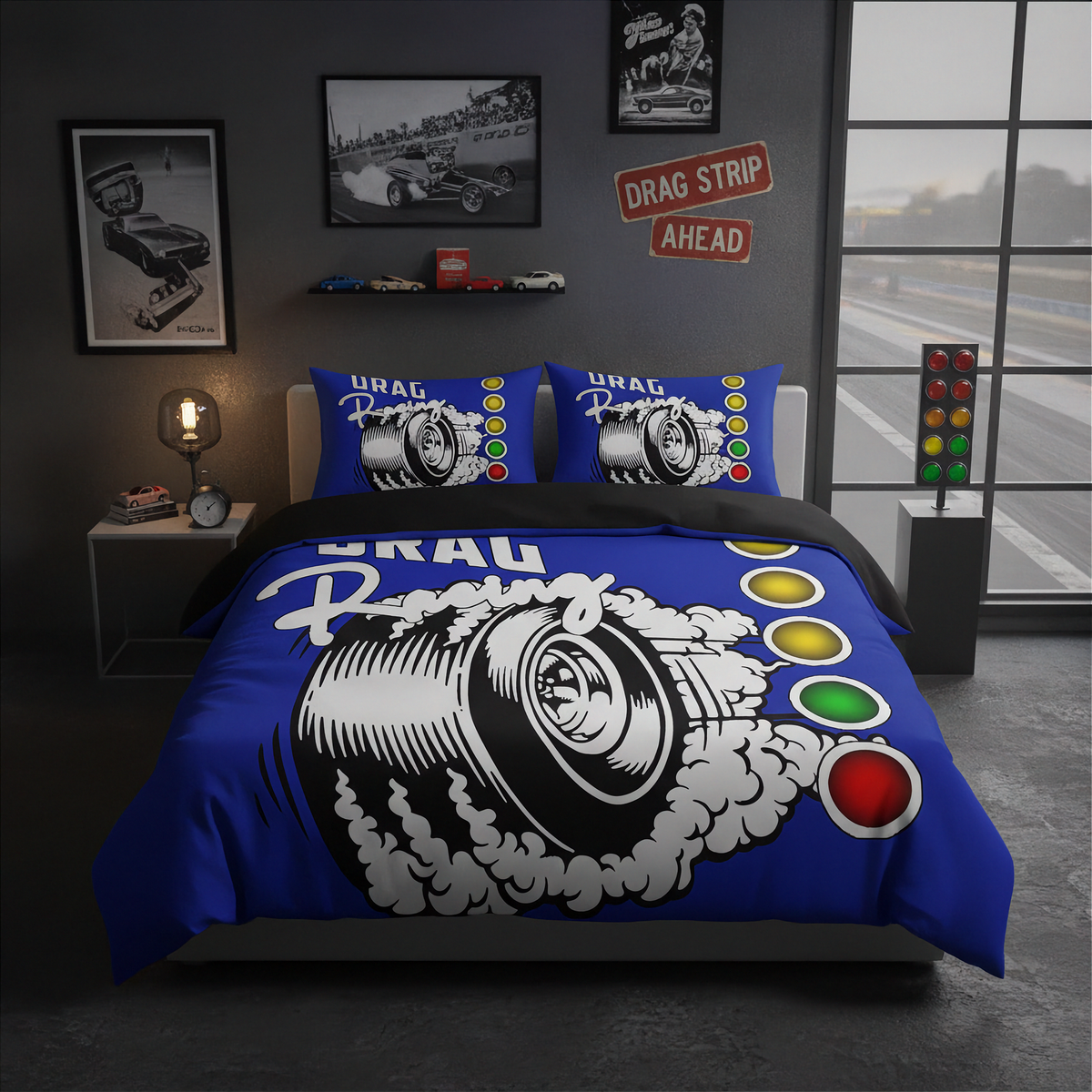 A racing-themed bedding set featuring a blue duvet cover and matching pillowcases with a large black-and-white tire graphic, smoke, and colorful drag strip light buttons, styled in a dark gray bedroom with racing decor.
