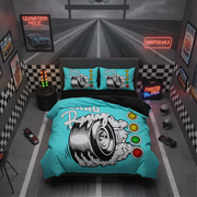 A bedroom styled like a race track, centered on a bed with a bright turquoise racing-themed bedding set. The duvet and two matching pillowcases feature a large black-and-white tire graphic with smoke and the word 'Quartzy,' plus racing light buttons.