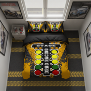 A racing-themed bedding set displayed on a bed in a styled bedroom. The set includes a duvet cover and two pillowcases featuring a yellow and black drag racing graphic with a stylized traffic light pattern and the words 'STAGE DRAG RACING'.