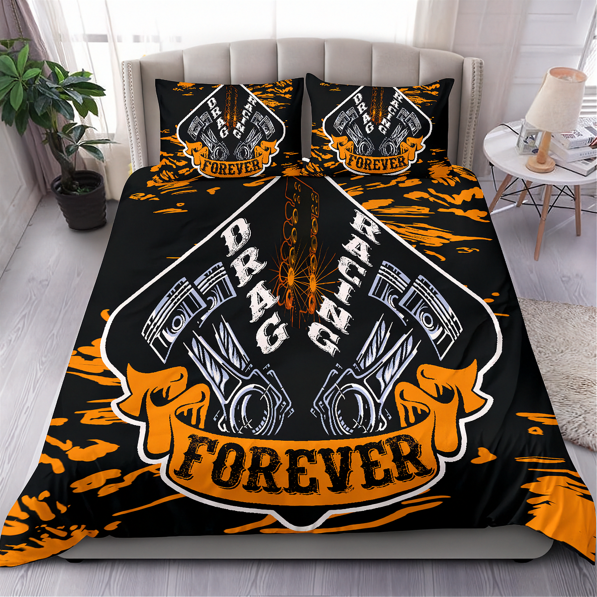 A bed dressed in a black bedding set with a bold orange and white racing graphic featuring pistons, flames, and the words 'DRAG RACING FOREVER', shown in a styled bedroom with a side table, lamp, plant, and window.