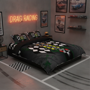 A bed dressed in a dark gray and black drag racing themed bedding set, featuring a checkered flag pattern and a colorful striped finish line graphic. The room is styled with a neon 'DRAG RACING' sign, vintage car posters, and miniature race cars on shelves.