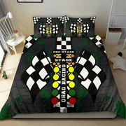 A racing-themed bedding set featuring a duvet cover and two pillowcases with a drag racing track design, checkered flags, and colorful buttons on a black background, shown on a bed in a bedroom setting.