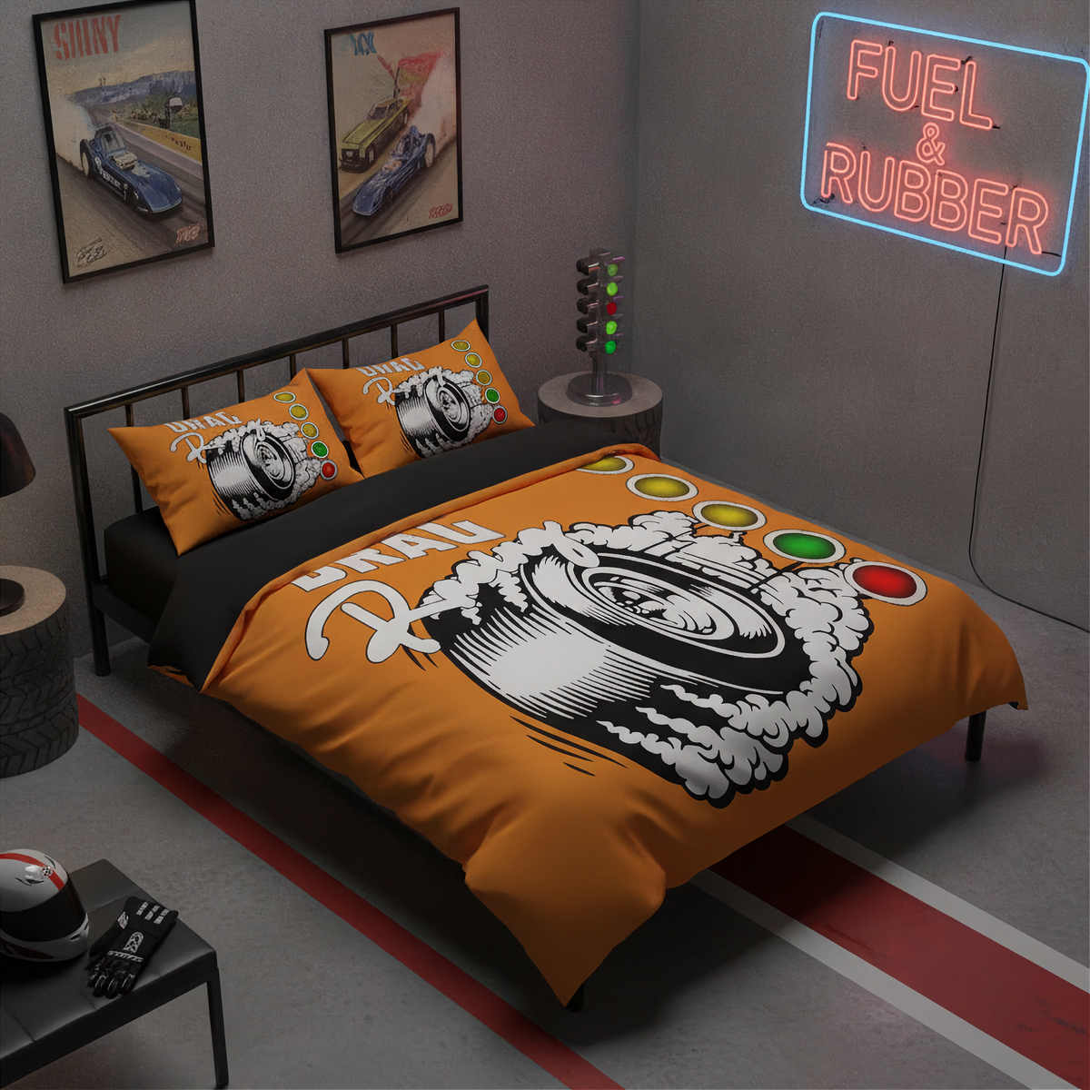 A bed dressed in an orange racing-themed bedding set with a large tire graphic and 'Fuel & Rubber' text, styled in a gray room with framed car posters, a neon sign, and racing decor.