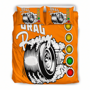 An orange bedding set featuring a duvet cover and two matching pillowcases with a drag racing graphic. The design includes a large black and white tire with smoke, the words 'DRAG Racing', and a vertical sequence of yellow, green, and red light circles.