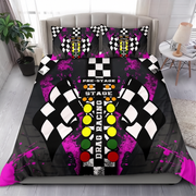 A bedding set featuring a duvet cover and two pillowcases with a drag racing theme, displayed on a bed in a modern bedroom setting. The design includes black and white checkered flags, a central starting-line motif with yellow, green, and red lights, and bright pink paint splatters on a black background.