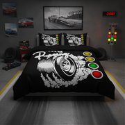 A racing-themed bedding set displayed on a bed in a garage-style room. The set includes a black comforter and two matching pillowcases featuring a large white car wheel graphic with smoke effects and colored light bulbs.