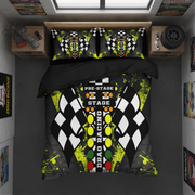 A racing-themed bedding set displayed on a bed in a modern, dark-themed room. The set includes a duvet cover and two matching pillowcases featuring a black and white checkered flag design, neon yellow paint splatters, and a vertical track button graphic with 'PRE-STAGE', 'STAGE', and 'DRAG RACING' text.