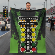 Man on a drag track holding a green drag racing blanket