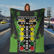 Woman holding a 'Pre-Stage Stage Drag Racing' banner at a race track.