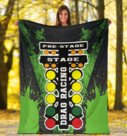 Woman holding a large green and black 'Drag Racing' blanket with colorful text in a forest setting.