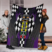 Two people holding a large blanket with racing design and text.