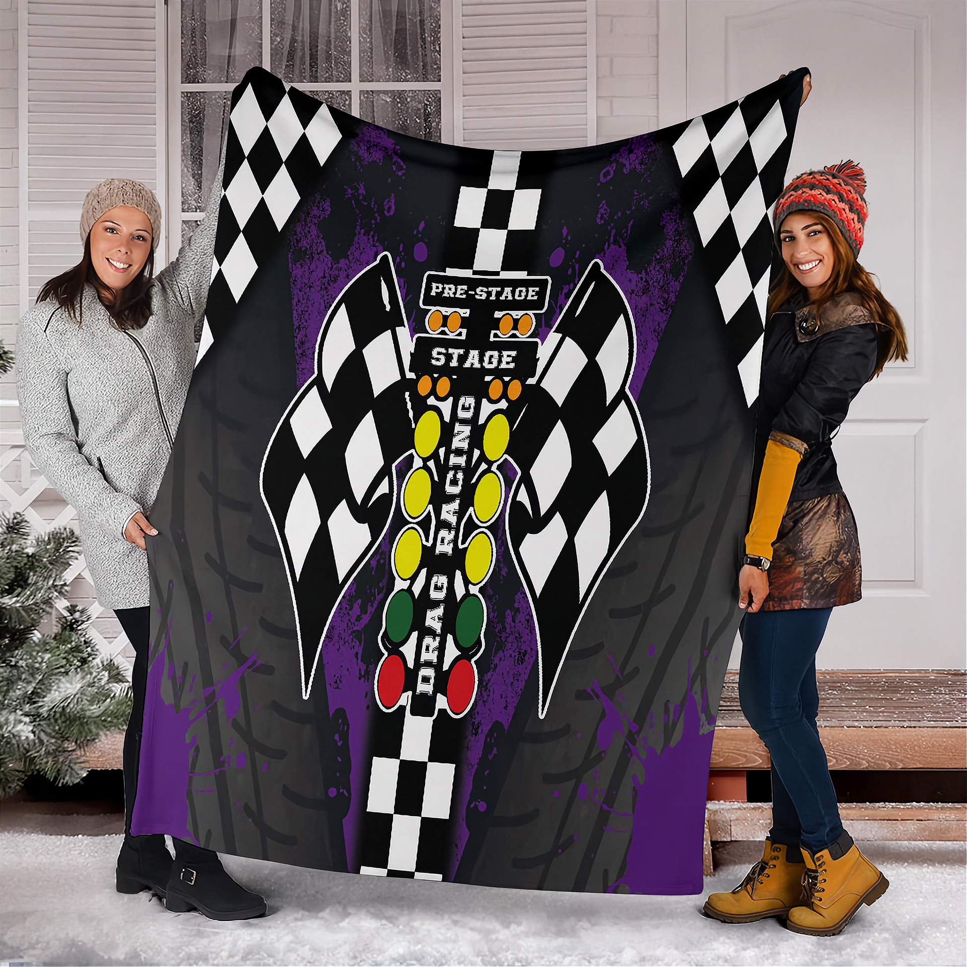 Two people holding a large blanket with racing design and text.
