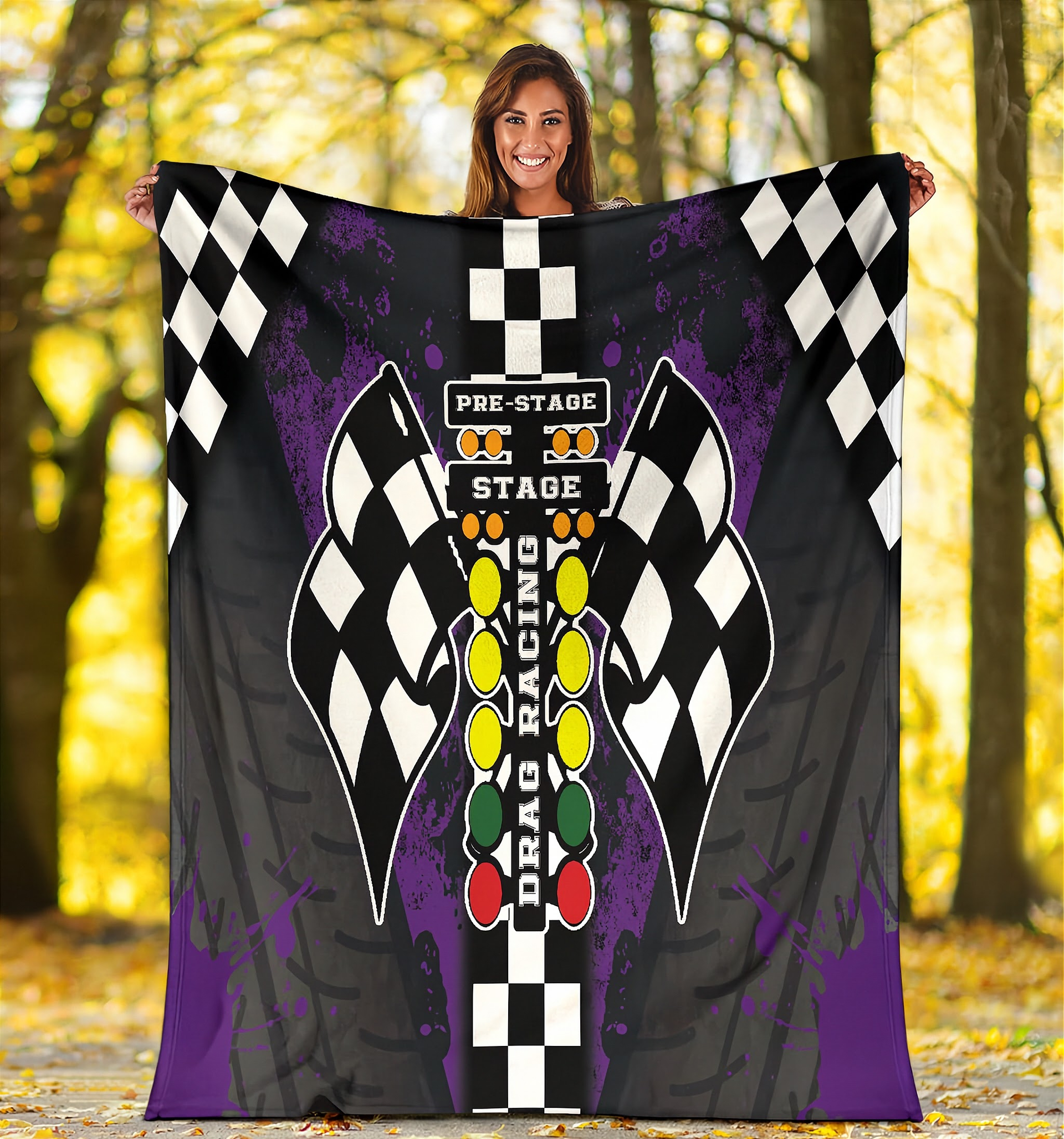 Woman holding a large decorative blanket with drag racing-themed design in a forest setting