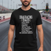 Man wearing a black t-shirt with 'Drag Racing Dad' text at a race track.