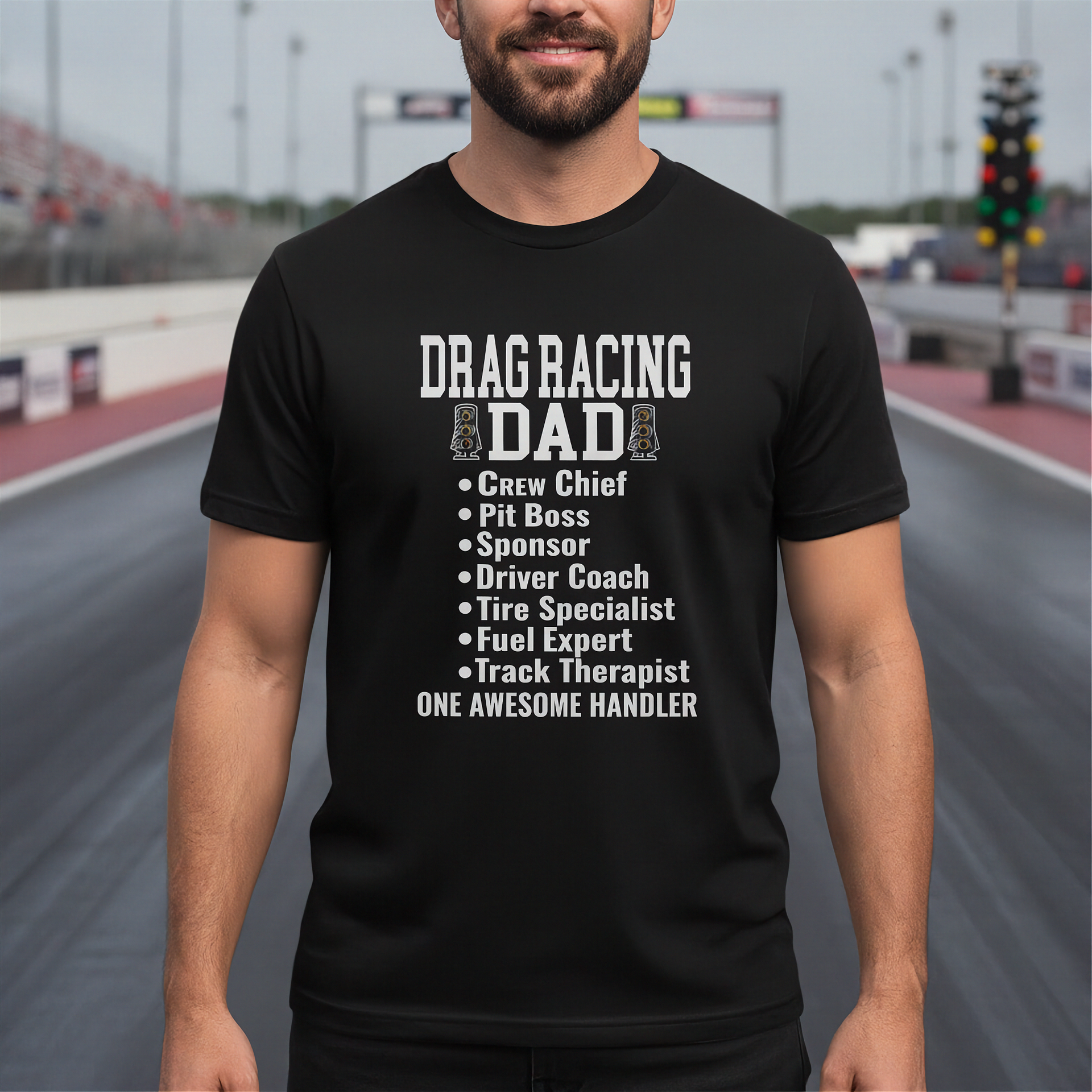 Man wearing a black t-shirt with 'Drag Racing Dad' text at a race track.