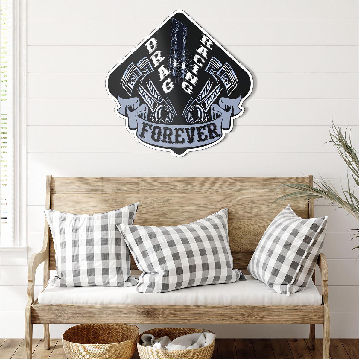 A die-cut metal sign featuring a black and gray 'Drag Racing Forever' shield design with pistons and a chain, displayed on a white shiplap wall above a wooden bench with gingham pillows.