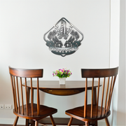 Wooden dining table with two chairs and a decorative drag racing metal wall art piece on a white wall.