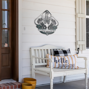 White bench with decorative pillows on a porch featuring a drag racing metal wall art piece.