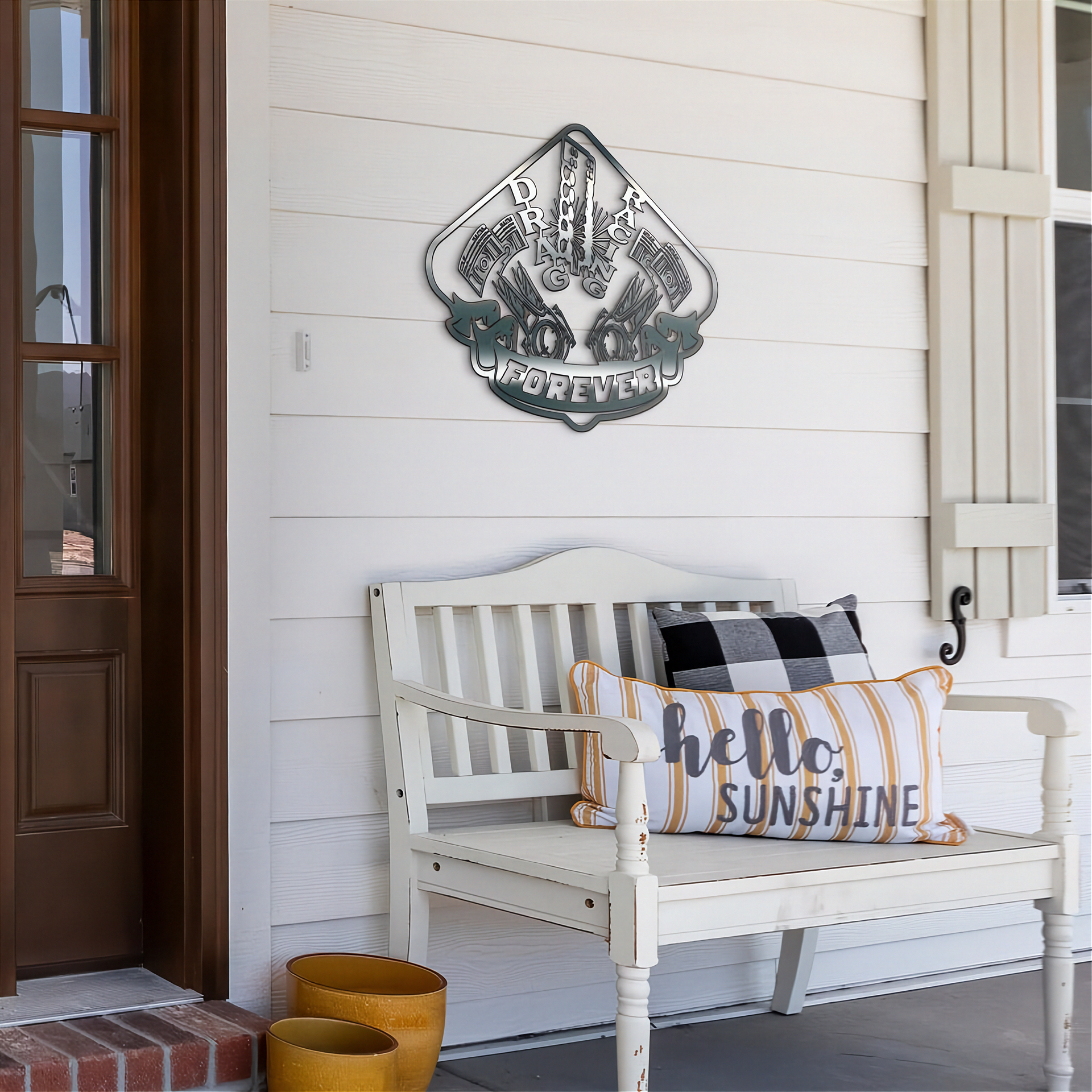 White bench with decorative pillows on a porch featuring a drag racing metal wall art piece.