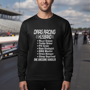 Person wearing a black sweatshirt with drag racing text at a race track.