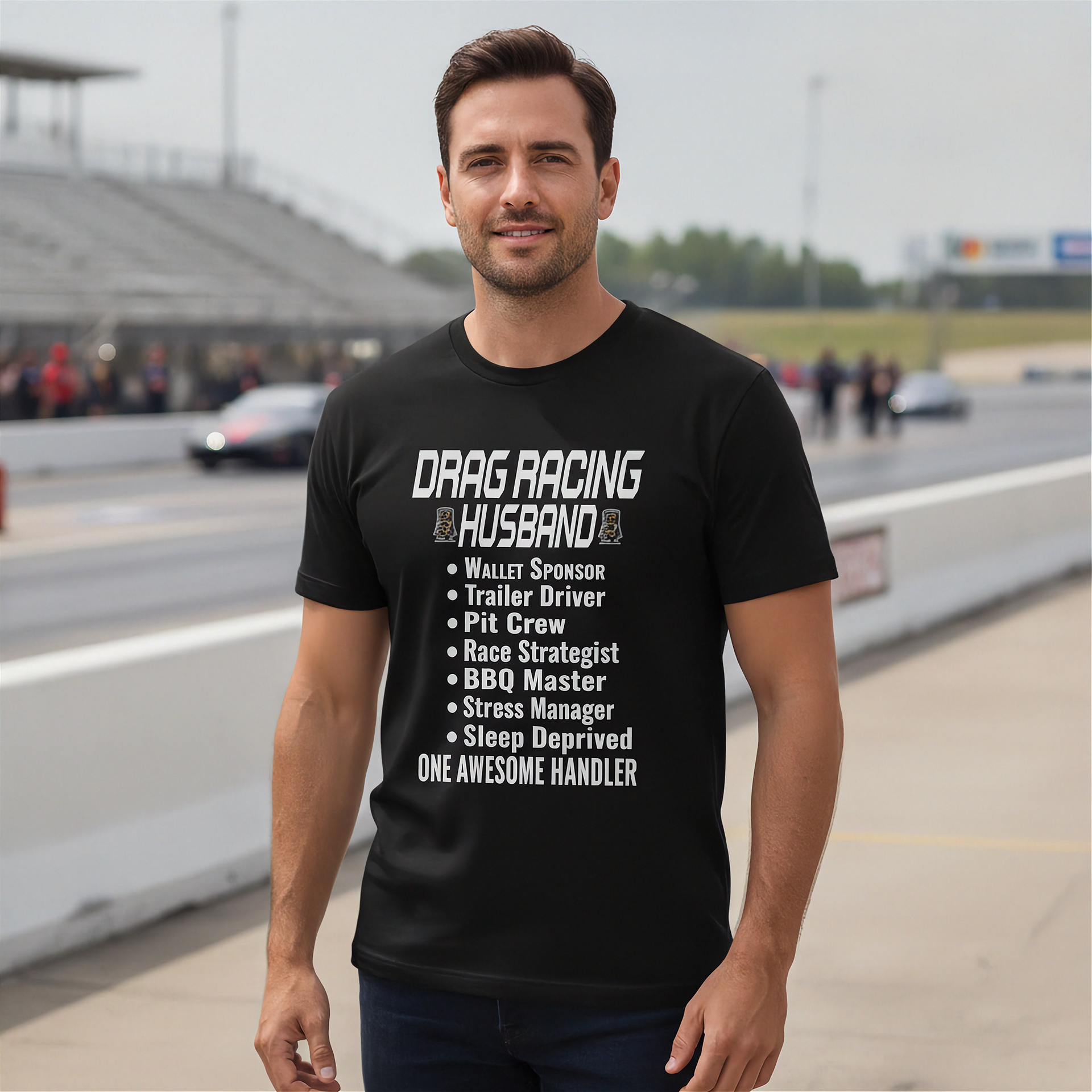 Man wearing a black t-shirt with drag racing husband at a race track.