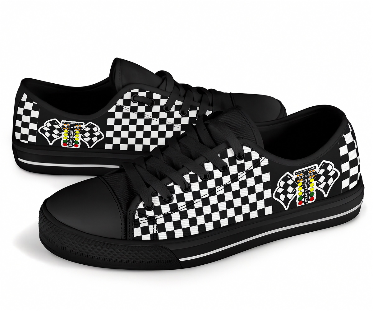 A pair of black low-top sneakers with a black and white checkered pattern on the sides, featuring a small graphic emblem on the heel area, set against a plain white background.