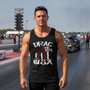 A muscular man stands on a drag racing track wearing a black tank top with a distressed American flag graphic and the words 'DRAG Racing USA'. A drag race car is visible in the background on the racetrack.