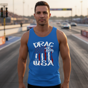 A muscular man stands on a racetrack wearing a bright blue tank top with a patriotic graphic that reads 'DRAG Racing USA' in white over a red, white, and blue American flag design.