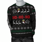 A black Christmas sweater with a festive knit pattern featuring white snowflakes, green zig-zag borders, reindeer, and the words 'HO - HO - HO' in red. The sweater is displayed on a gray mannequin torso with dark gray jeans against a plain white background.
