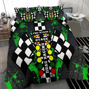 A bedding set featuring a drag racing theme, displayed on a bed in a modern bedroom setting. The set includes a duvet cover and two matching pillowcases with a graphic design of a checkered flag, green paint splatters, and racing lights on a black background.