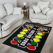 A rectangular black area rug with a drag racing theme, featuring a start line, 'DRAG RACING' text, and traffic lights in red, yellow, and green, shown in a modern living room setting.